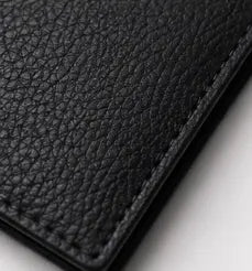 Gros plan sur le cuir véritable du portefeuille cuir homme noir révélant la texture et la qualité de finition